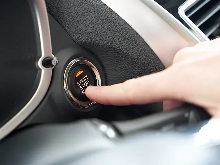A finger pressing a car's engine start-stop button, demonstrating the ignition on/off detection feature.