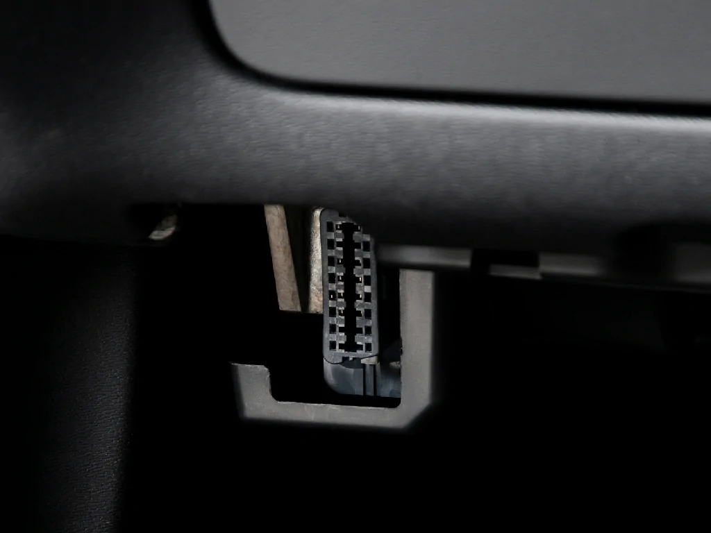 A close-up view of a vehicle's standard OBD-II port, where the GTB10 tracker connects for power and data.